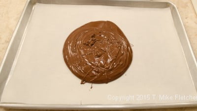 Melted chocolate poured into a sheet pan for TJ's Cowboy Bark
